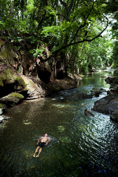 A swimmer relaxes in a Guatemalan jungle river