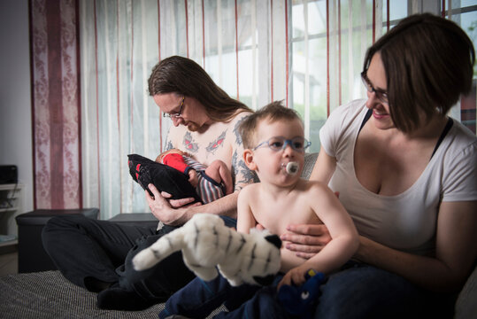 Portrait of Parents with newborn baby boy and little son sitting on the sofa
