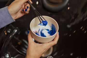girl in white rubber protective gloves holding a brush in her hands and stirring hair dye close-up...