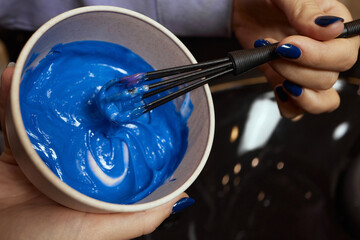 girl in white rubber protective gloves holding a brush in her hands and stirring hair dye close-up...