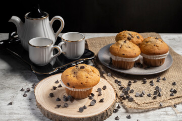 Muffin or cupcake with chocolate chips on wooden table background. Concept of making industrial or...