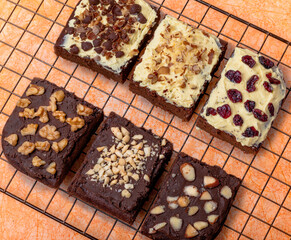 portions of chocolate brownies decorated with dried fruits peanuts nuts and seeds on a cooling rack