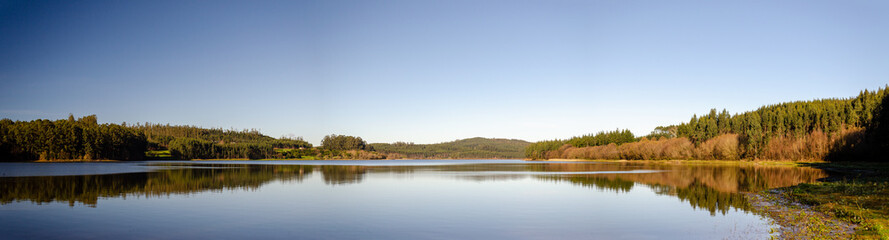 Panoramic view of a lake where the trees are reflected in a water
