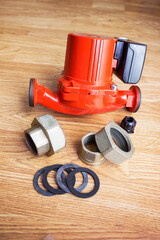 Red circulation pump for heating system and fasteners for it lies on the floor