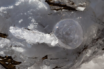 Macro photo of soap bubble on snow. Snow reflections. Winter landscape. Ice and snow.