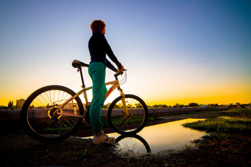 Girl on a mountain bike in the rays of the summer setting sun