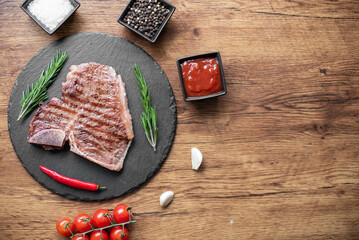 grilled T-bone steak on a cutting board with herbs on a wooden background with copy space for your...