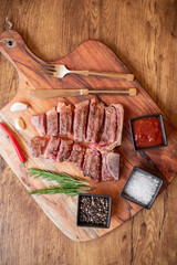 grilled T-bone steak on a cutting board with herbs on a wooden background