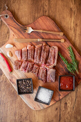 grilled T-bone steak on a cutting board with herbs on a wooden background