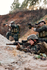 team of military soldiers, shooters wearing combat uniform, body armor and helmet, aiming service...