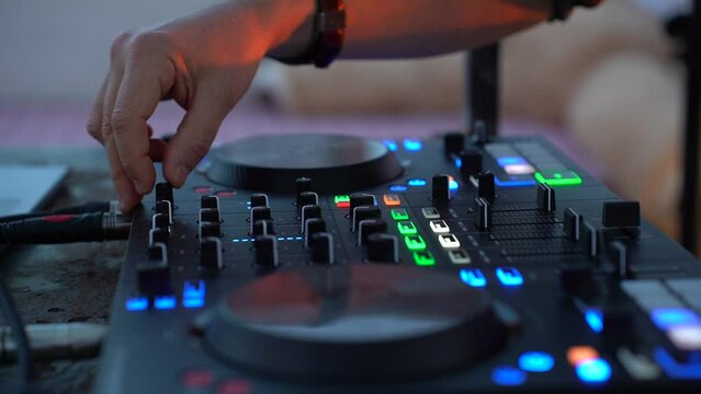 Dj mixing music outdoor at beach night party festival - Close up of sound mixer equipment - Focus on hand - Fun, millennials generation, youth lifestyle, entertainment and fest concept