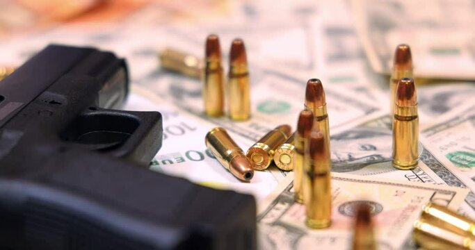 Gun and bullets on dollar and euro banknotes background, closeup shot. Criminal money. Black money and protection, mafia and corruption concept