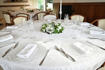 Table with cutlery and glasses in the restaurant. Wine glasses, flowers, fork