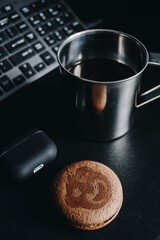 Morning coffee and cookies by the computer keyboard and headphones