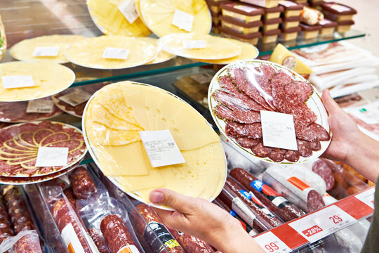 Sliced cheese and sausage in hands in store