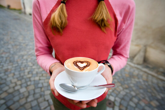 Woman holding coffee with heart shape in foam