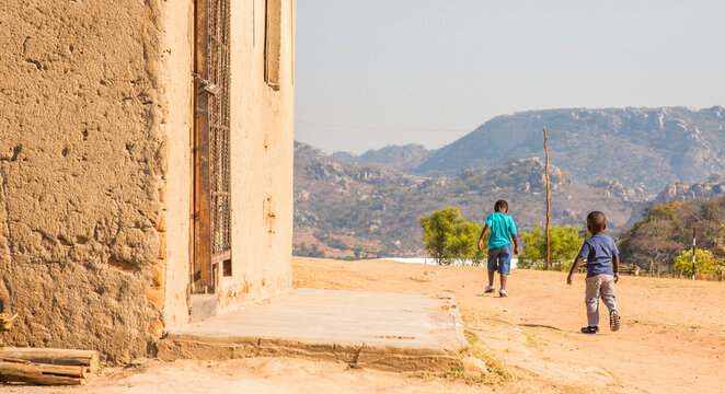 Two boys walk through their Zimbabwean village