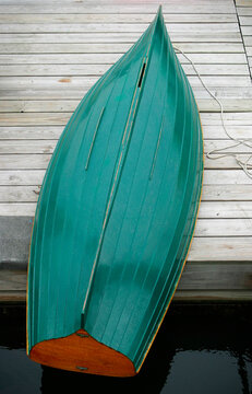 Row boat with shiny green bottom at rest on a dock.