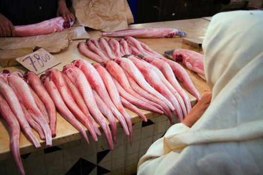 A fishmonger selling fish to a Muslim woman wearing white Hijab.