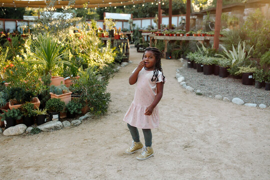 Young Black Girl With Long Hair Near Among Plants At Nursery