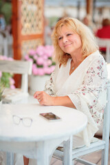 Portrait of woman sitting on the terrace of a beach cafe on a summer sunny day