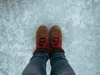 Low section of woman wearing boots while standing on frozen Lake George