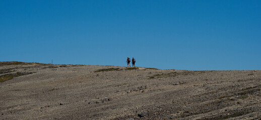 Fototapeta na wymiar Two active hikers walking on exposed mountain ridge path trail in Nelson Lakes National Park Southern Alps New Zealand