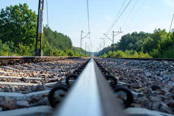Tory kolejowe z niskiej perspektywy z widoczną  siecią trakcyjną 