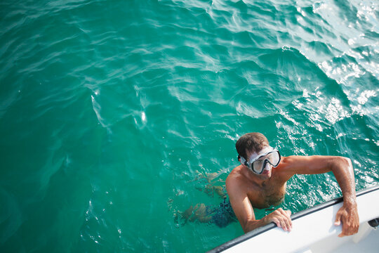 A man in a diving mask swims climbs in a boat in the ocean off Wrightsville Beach, NC.