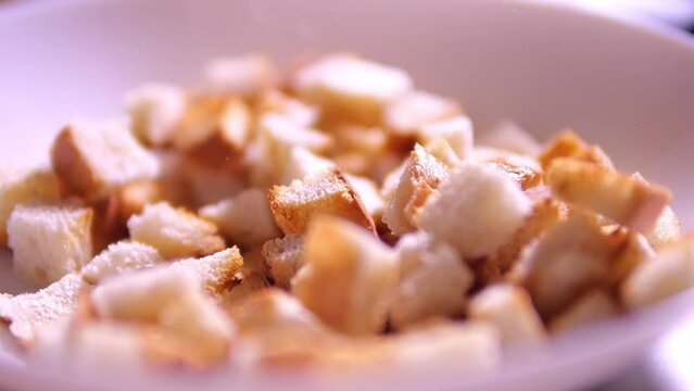 Crackers from white bread are poured into a plate. Bread cubes for cooking.