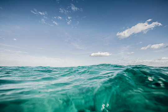 A Surface View Of Turquoise Ocean Water With Blue Sky And Clouds