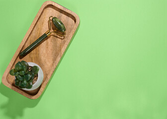 Jade facial massager, an item for cosmetic procedures on a green background