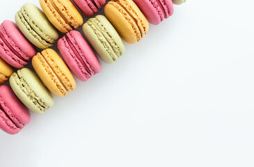 Multicolored almond flour macaroon cookies on white background. Selective soft focus, space for text