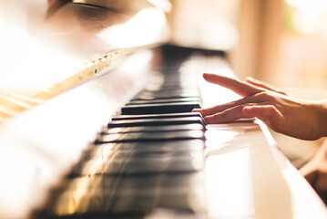 Close up image of child's hand playing piano in a sunny room.