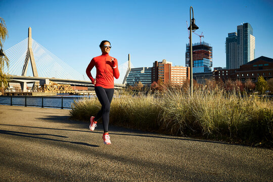 A fit woman runs past the Boston skyline.