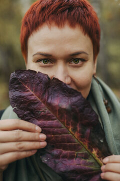 Woman of 30-40 years old with burgundy leaf, her face is covered