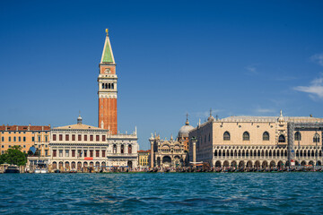Fototapeta na wymiar Authentic view of Piazza San Marco from the water on a sunny day, real tourists on the main street of Venice near the seaside admire the beautiful sights, interesting holidays and travels in Italy