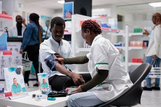 Pharmacist consultation, medic measuring patient blood pressure. Woman examining african american man health in drugstore, cardiovascular disease diagnostic, medical check up