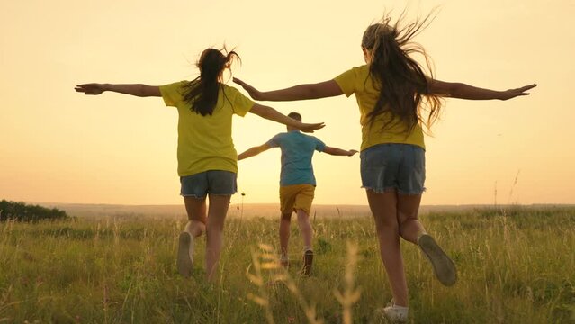 Children run together in park, sunset. Friends dream of flying on an airplane, to be pilots. People in park concept of festive happiness having fun. Happy family. Happy family son, daughter. Сhild run