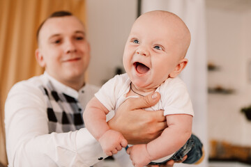 Little boy happy funny smiling laughing cute child baby, father hold lift the child. Playful toddler with bulging eyes having fun, making faces grimaces. Happy childhood, family concept
