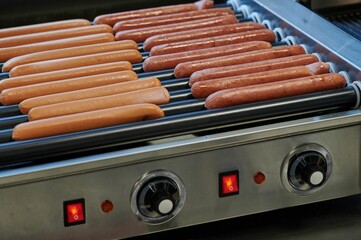 hot dog sausages on rolls of heating device