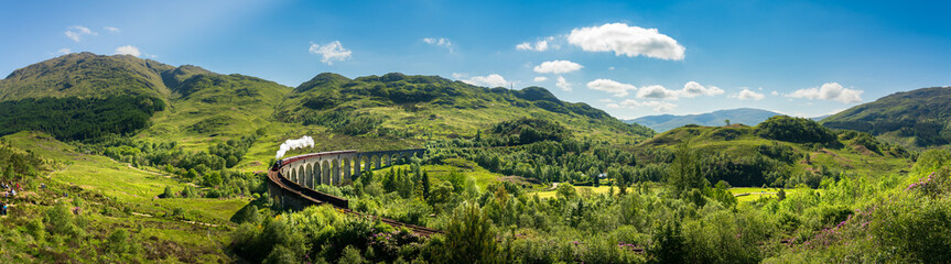 Fototapeta na wymiar Glenfinnan Railway Viaduct in Scotland with the steam train passing over
