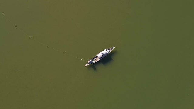 Lonely fisherman in vast river of Surma, aerial top down spin view