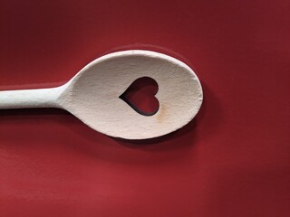 carved heart in a wooden spoon on a red background
