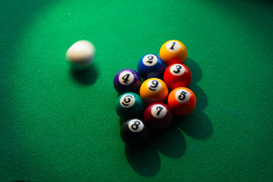 Miss shot. Near miss. Cue ball missing the opening break shot. A nine ball rack and a blurred cue ball on a billiard or pool table. shallow depth of field.  