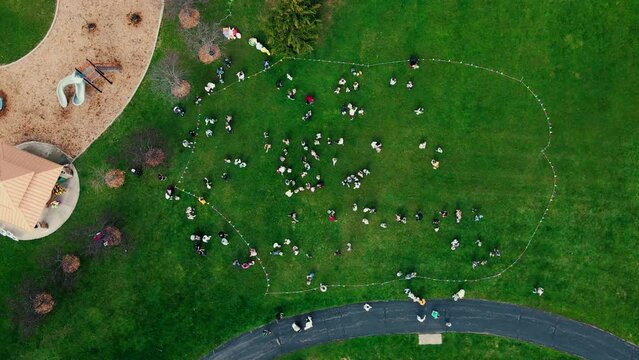 top down aerial of easter egg hunt event at a large park in Plainfield Illinois. Children and parents runing in a circle to gather as many eggs as possible on the Easter Holiday