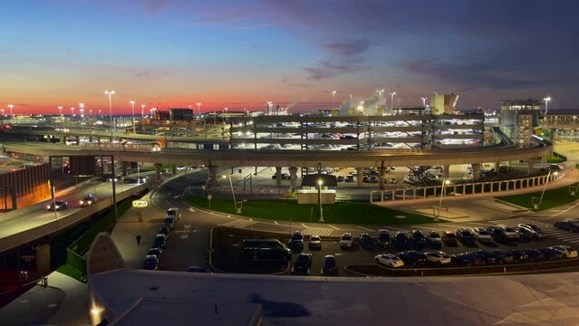 Airtrain JFK travels the elevated railway on a thoroughfare past the parking garage at New York Airport as the sky is tinted by the setting sun. steady shot