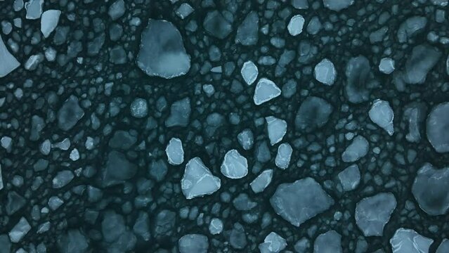 Large ice floes gently moving in the waves of the sea. Top down lifting and rotating shot