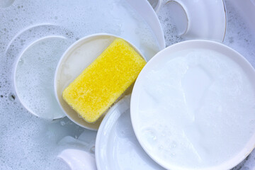 Dishes and bowls in water and bubbles of dishwashing liquid