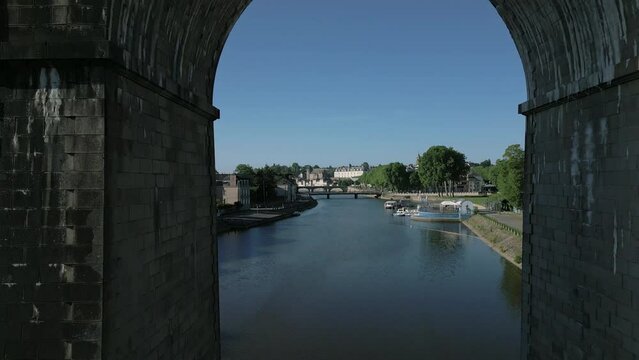 Drone passing between arches of railway bridge in Laval, Mayenne, France. Aerial forward ascending and sky for copy space